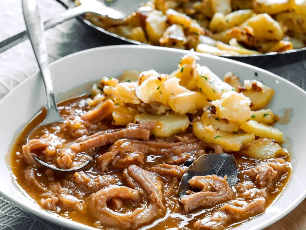 Herzhaftes Kutteln Rezept mit goldbraunen Bratkartoffeln, garniert mit Petersilie. Ein Löffel voller Genuss.