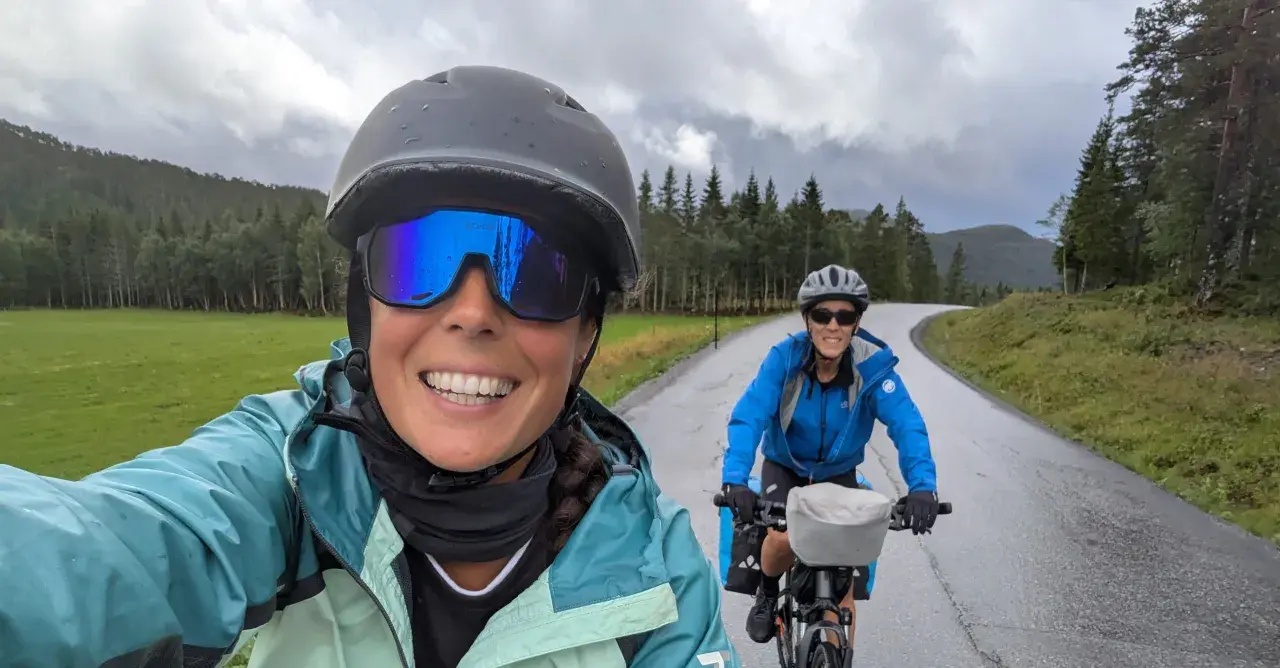 Dos ciclistas disfrutan de una ruta en bicicleta por un paisaje verde y montañoso, ¡una aventura EuroVelo España!