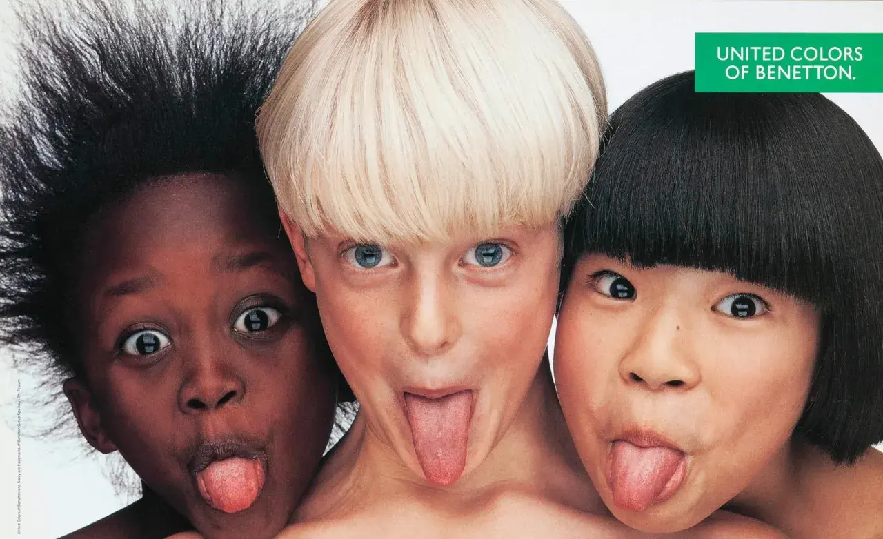 Tre bambini di etnie diverse, in una delle fotografie famose a colori di Oliviero Toscani, fanno la linguaccia.