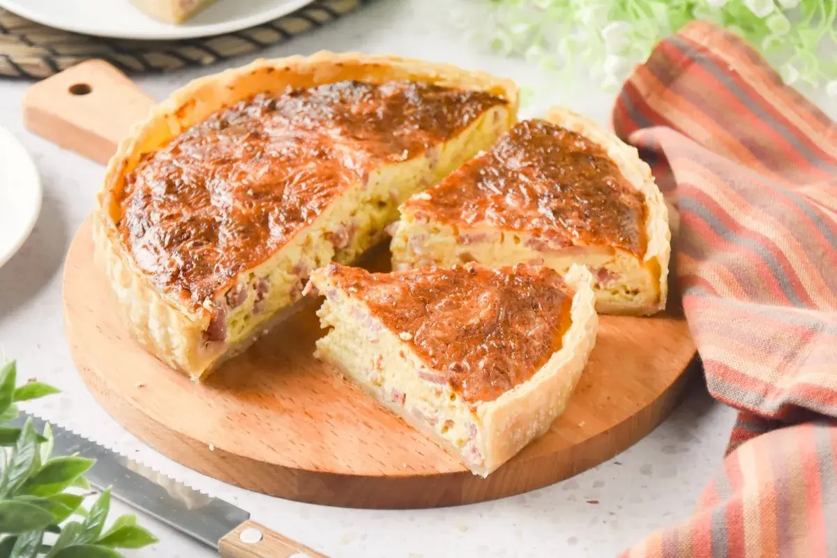 Un delicioso quiche de bacon, recién horneado y cortado en porciones, listo para disfrutar.