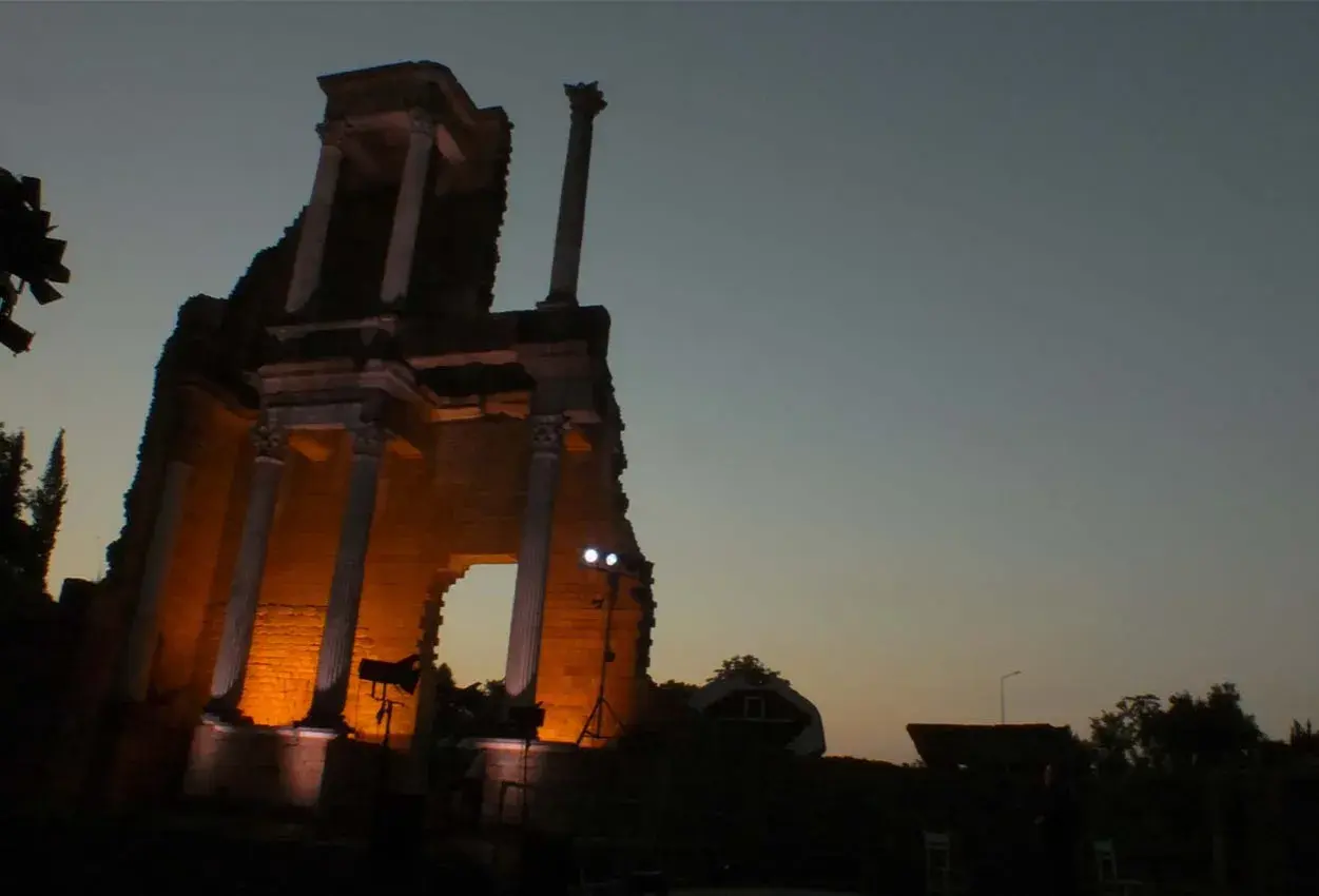 Il teatro romano di Volterra illuminato di sera, con le sue antiche colonne che emergono dall'ombra.