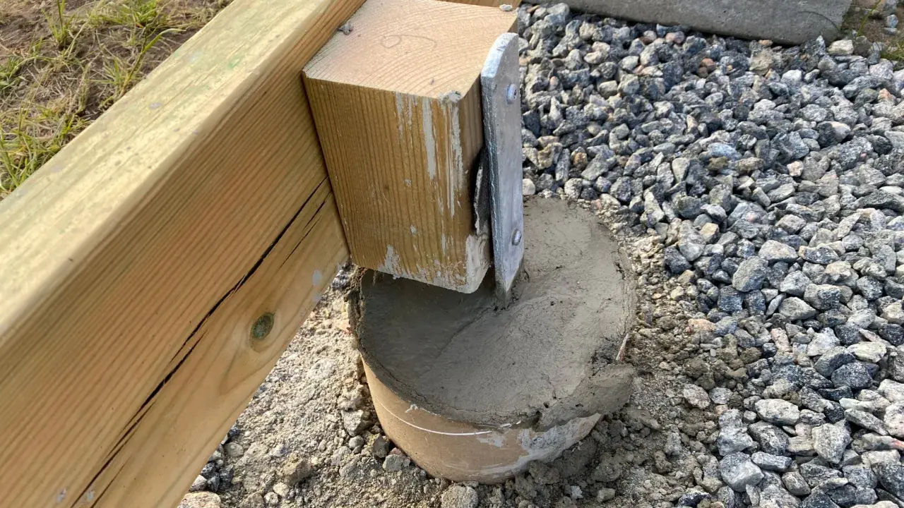 Nygjuten betong runt en stolpe som ska bära en altan. Plintavståndet är viktigt för stabiliteten.