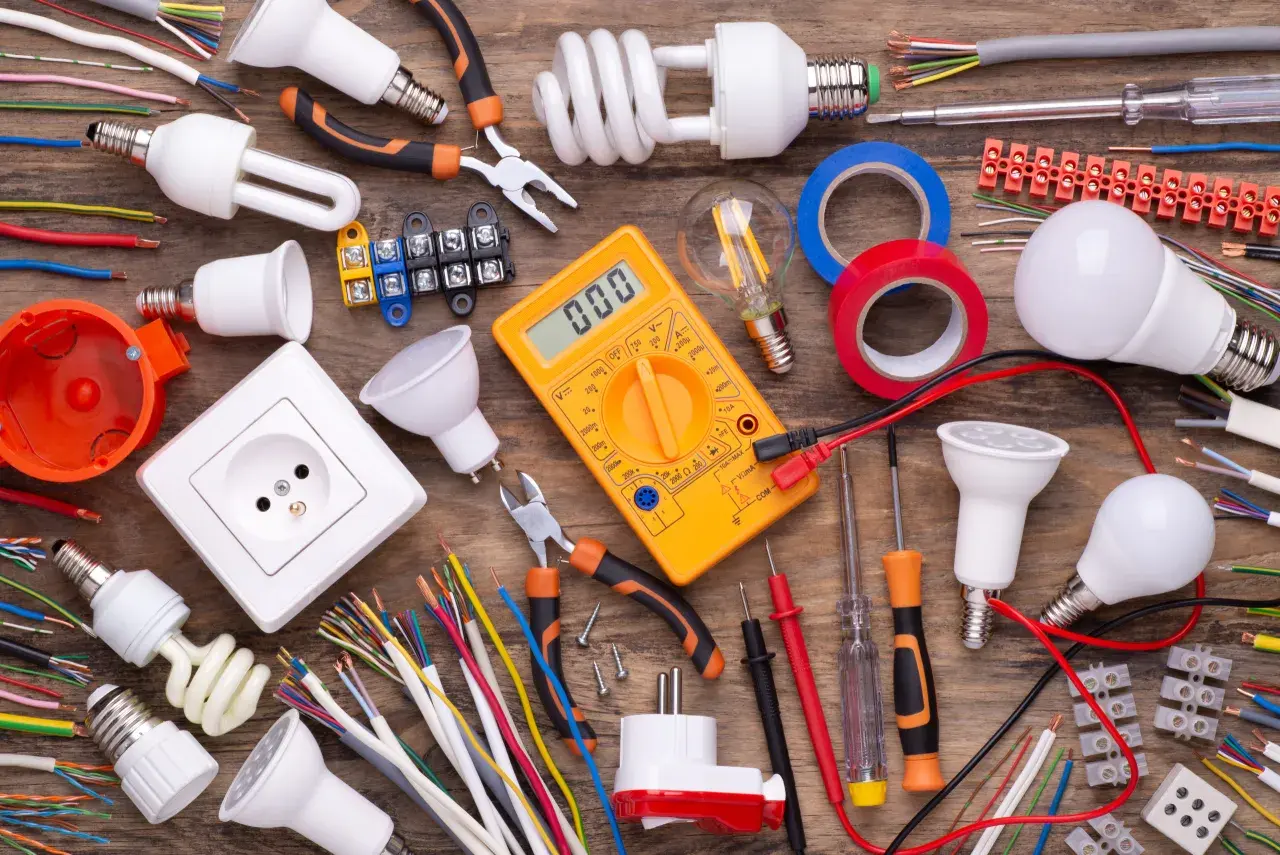 Wszystkie potrzebne materiały do instalacji elektrycznych: kable, żarówki, gniazdko, miernik, taśmy i narzędzia. Idealne dla hurtowni kabli i osprzętu elektroinstalacyjnego.