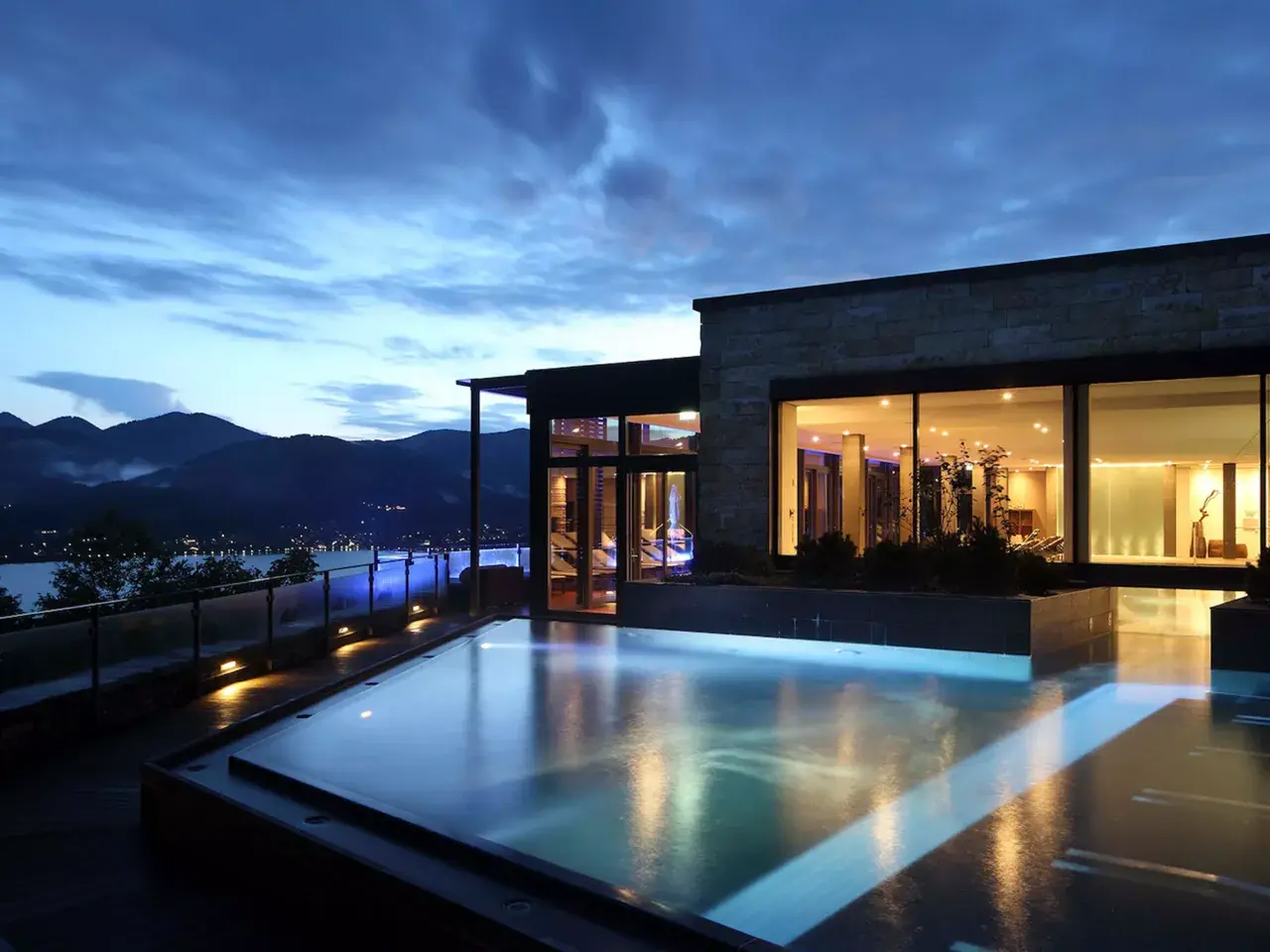 Ein luxuriöser Pool mit Blick auf die Berge und einen See. Perfekt für einen entspannten Urlaub in den Bergen.