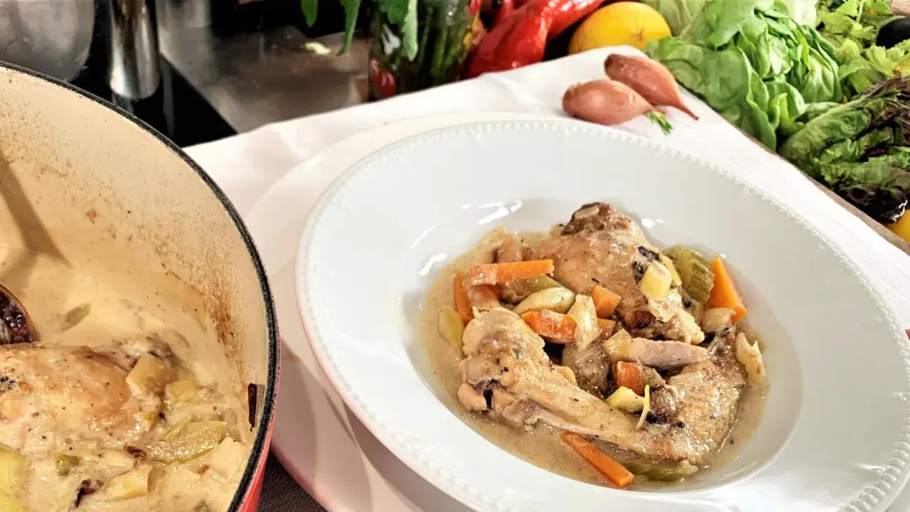 Coq au Riesling nach Martina und Moritz Rezept: Hähnchenteile in cremiger Sauce mit Karotten und Sellerie, daneben ein Kochtopf.