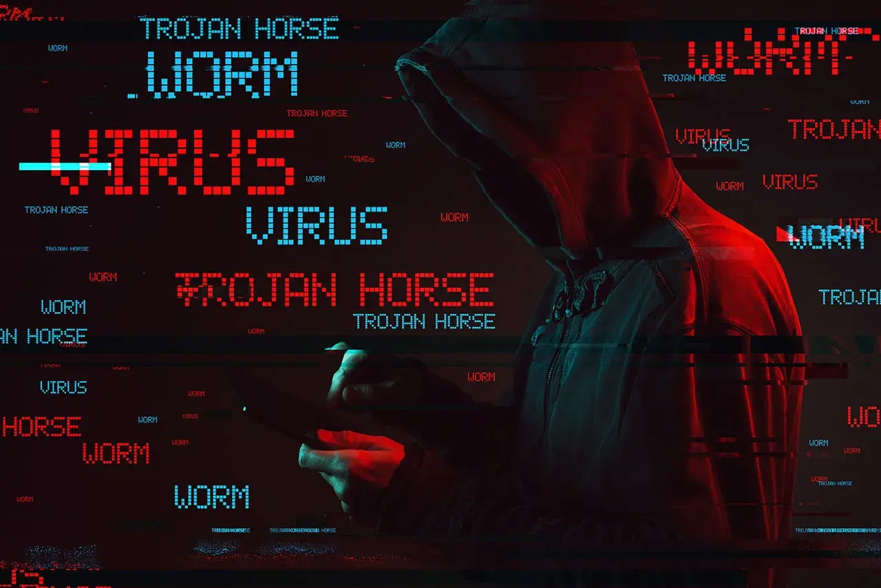 Haker w kapturze, otoczony przez migoczące napisy "WORM", "VIRUS" i "TROJAN HORSE". To pokazuje, co to trojan - złośliwe oprogramowanie udające coś pożytecznego.