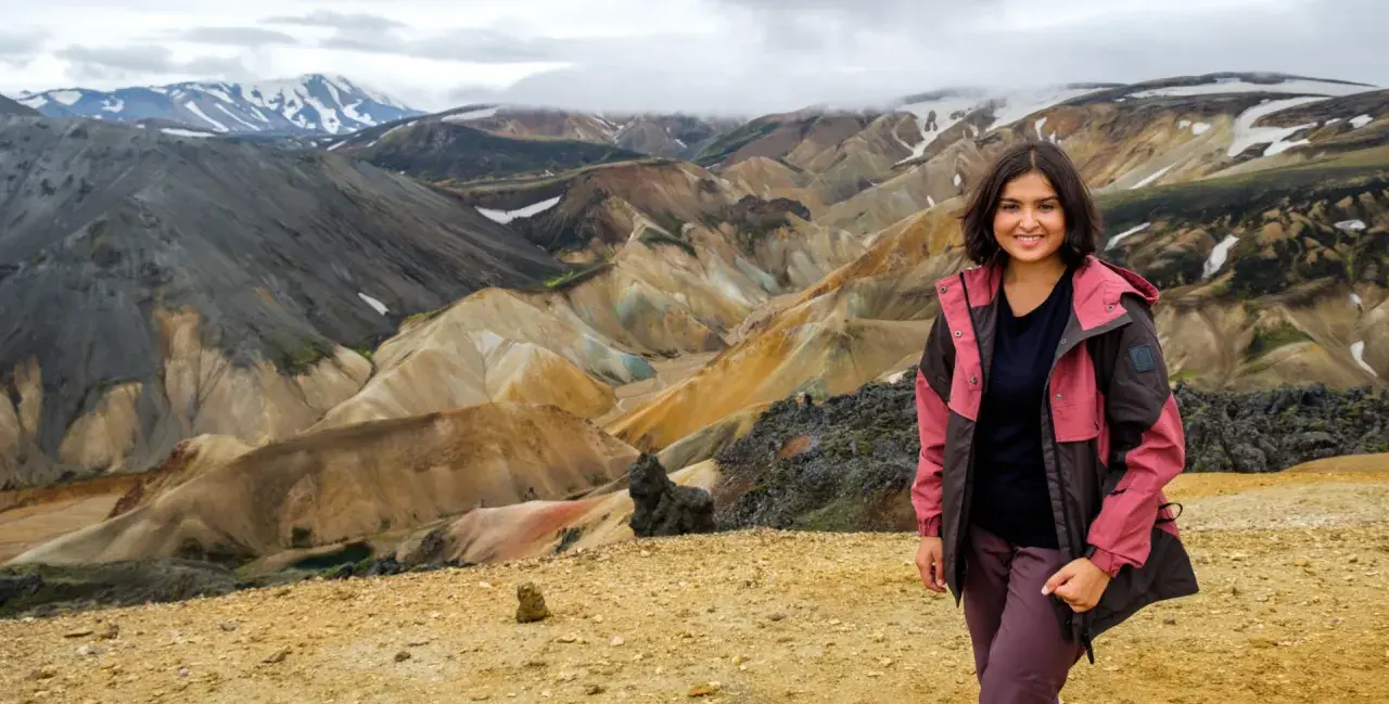 Uśmiechnięta kobieta na tle barwnych gór Landmannalaugar na Islandii.