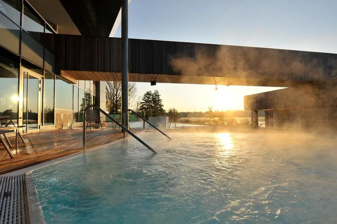 Dampf steigt aus einem Pool auf, während die Sonne über Brandenburg aufgeht. Ein perfekter Ort für einen erholsamen Urlaub.