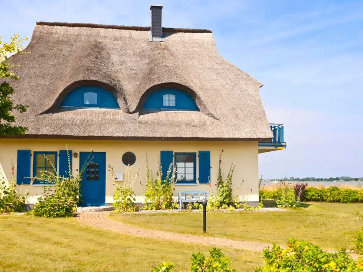Charmantes Haus mit Reetdach und blauen Akzenten. Ein Blick auf die Frage: was kostet ein reetdach?