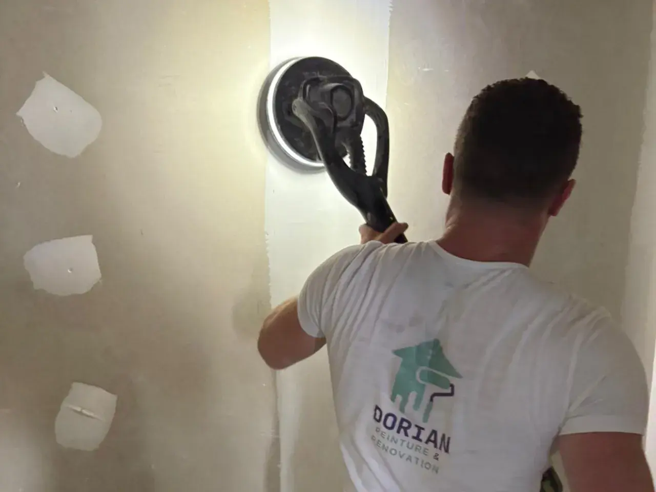 Un artisan utilise une ponceuse girafe pour lisser un mur en placo. C'est la ponceuse idéale pour un travail de finition impeccable.