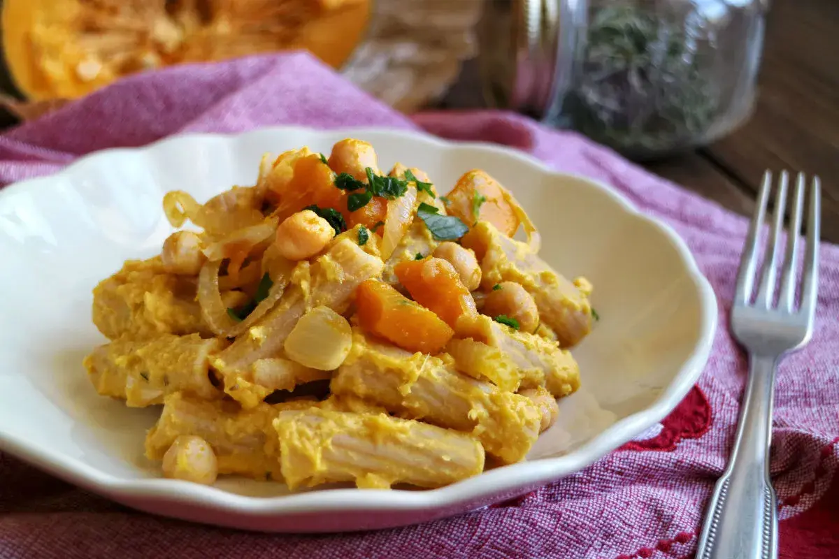 Piatto di pasta con la zucca, ceci e cipolla, guarnito con prezzemolo fresco. Un comfort food autunnale.