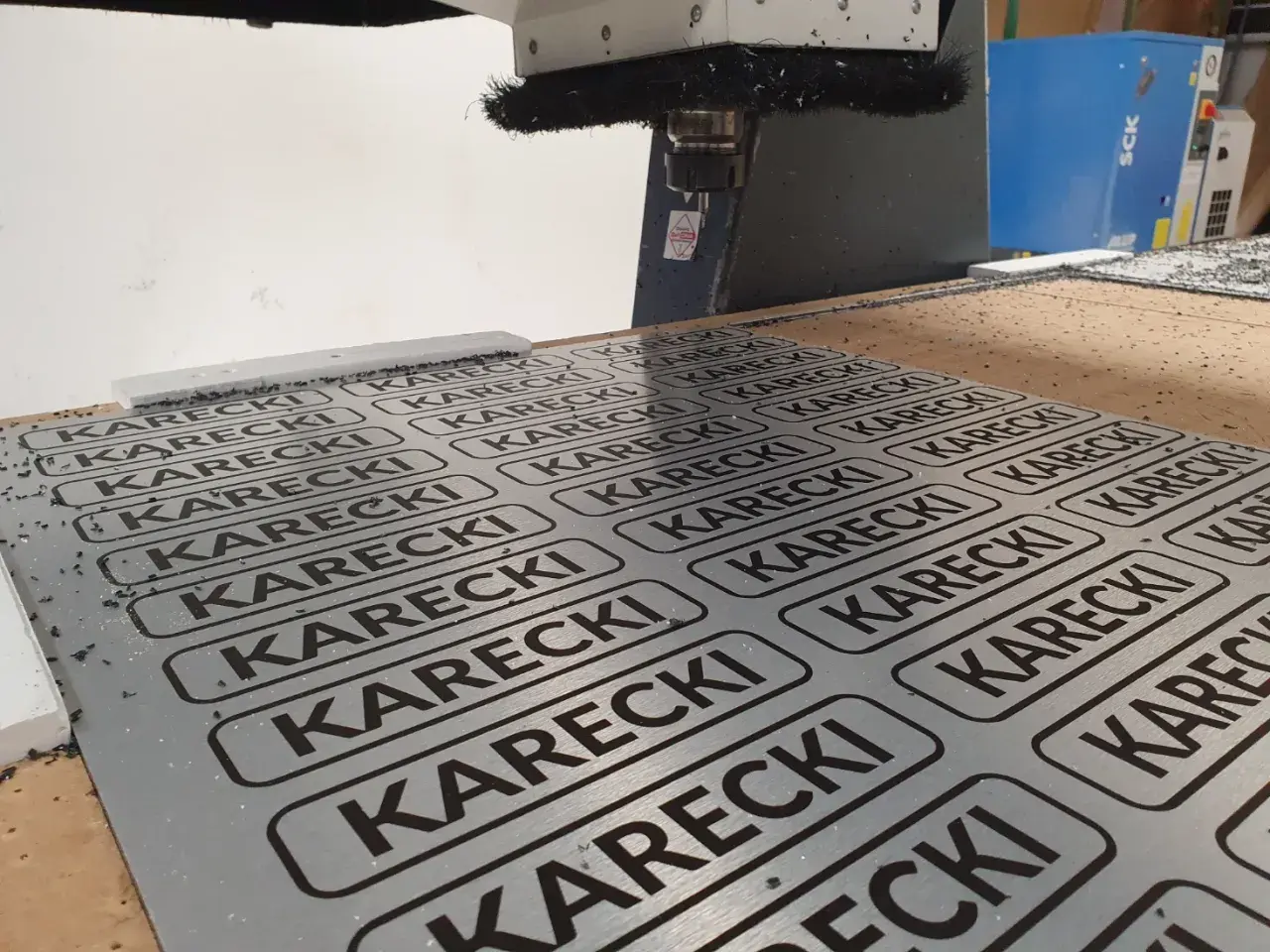 Cięcie CNC na płycie alu dibond z powtarzającym się napisem KARECKI.