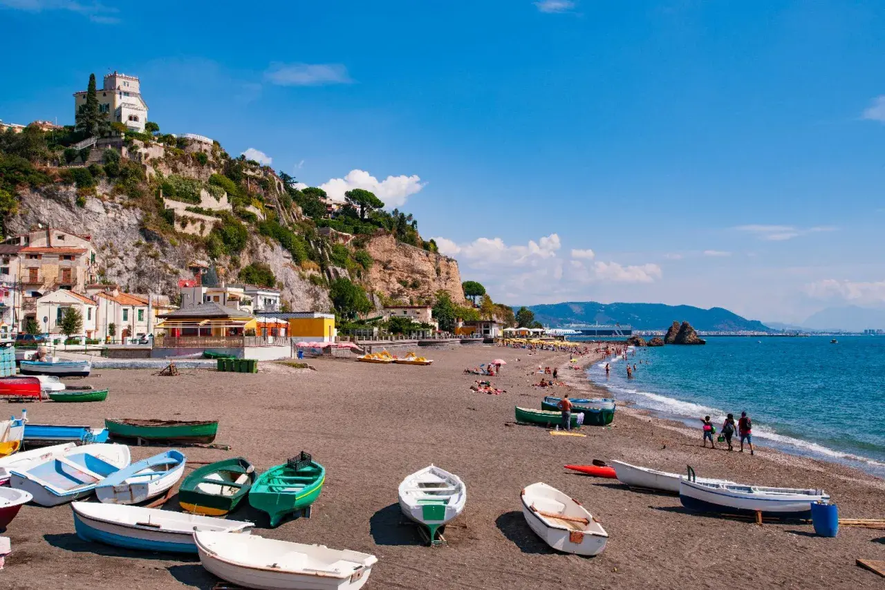 Spiagge Vietri sul Mare con barche sulla sabbia scura e case aggrappate alla scogliera.