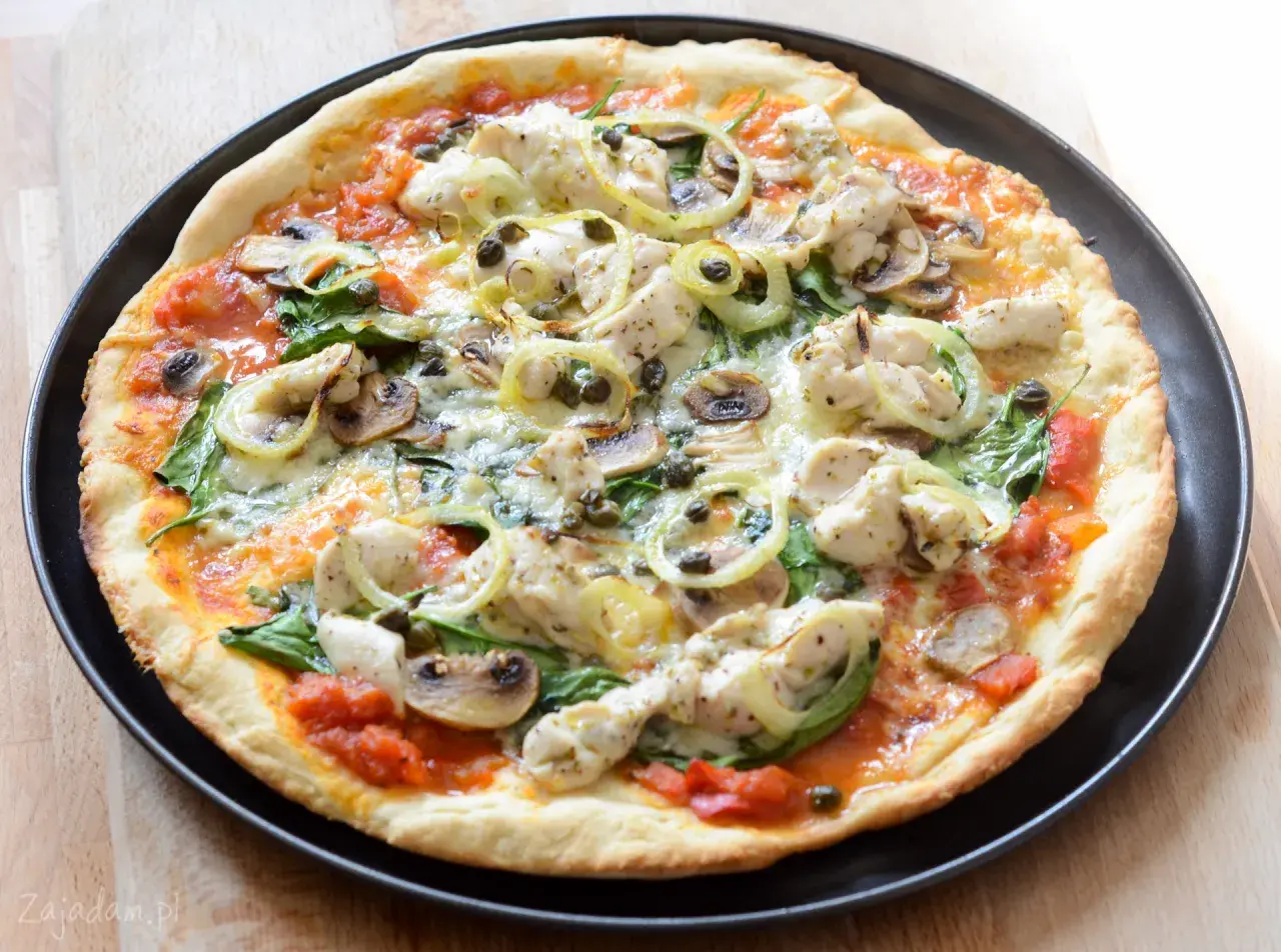 Pyszna pizza z kurczakiem, pieczarkami i szpinakiem, polana sosem pomidorowym.