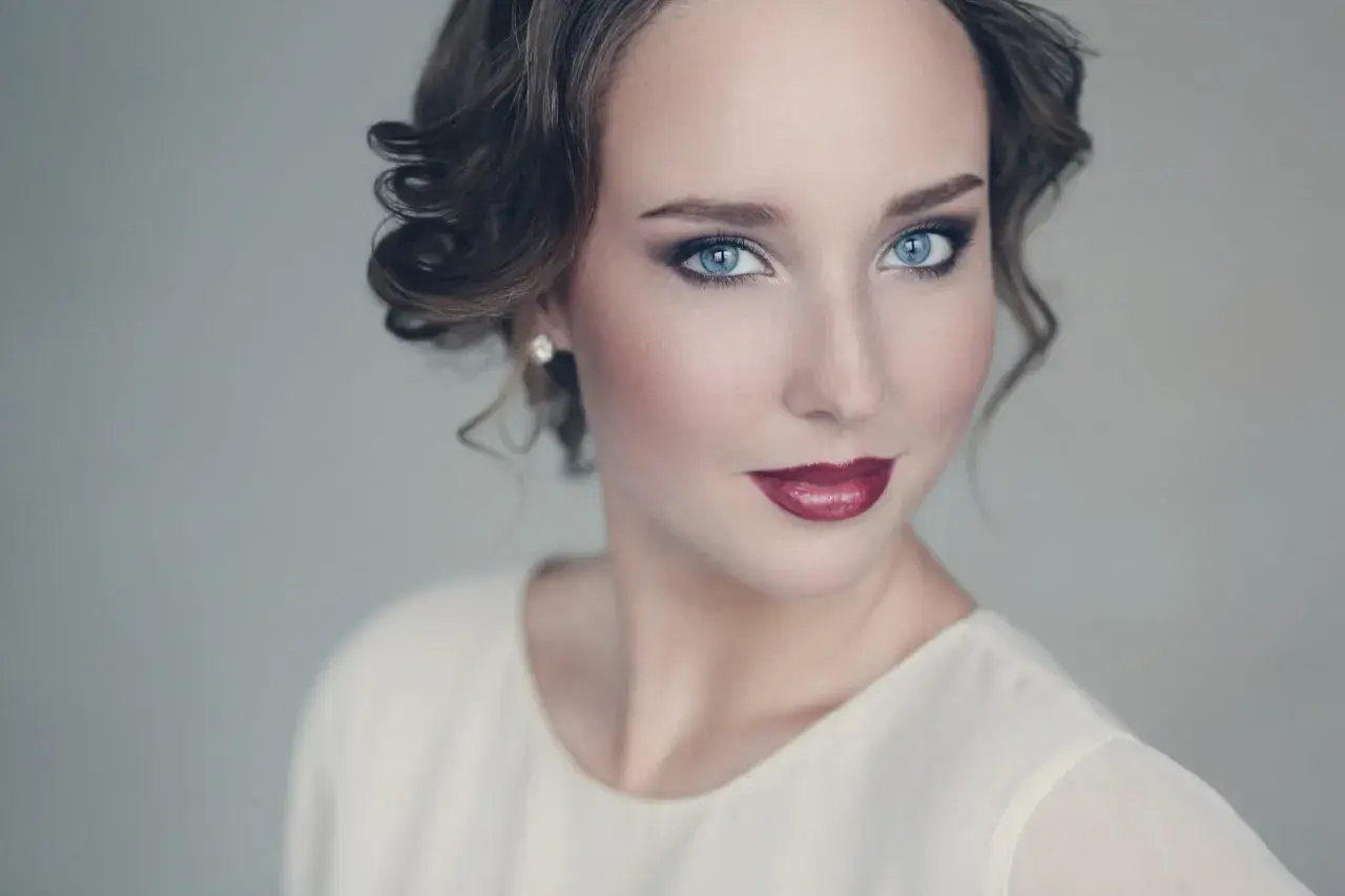 Maquillaje para vestido blanco: ojos ahumados, labios rojos y peinado recogido.