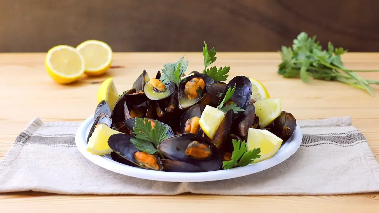 Un piatto invitante di impepata di cozze, guarnito con spicchi di limone fresco e prezzemolo, pronto per essere gustato.