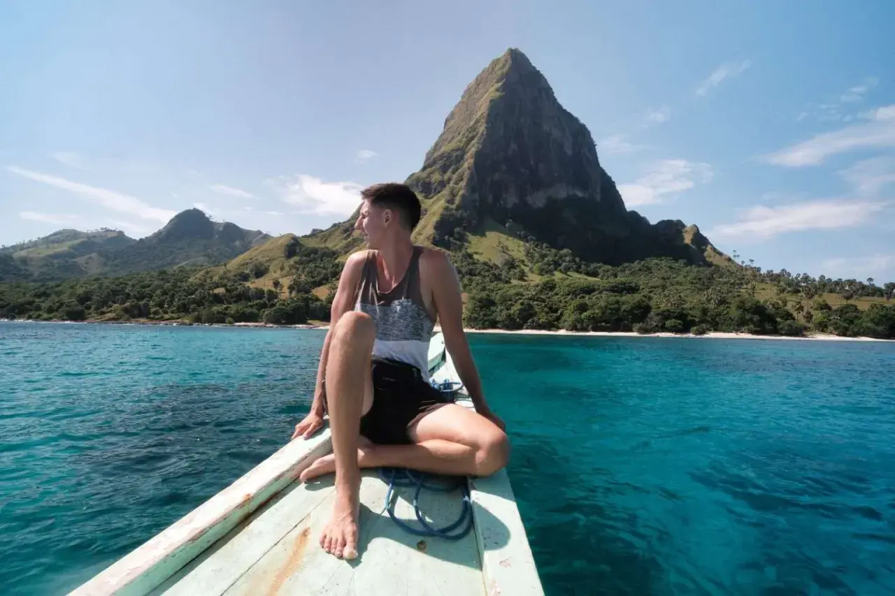 Mann auf Boot vor Bergkulisse in Indonesien. Tolle Reisetipps für dieses Inselparadies!