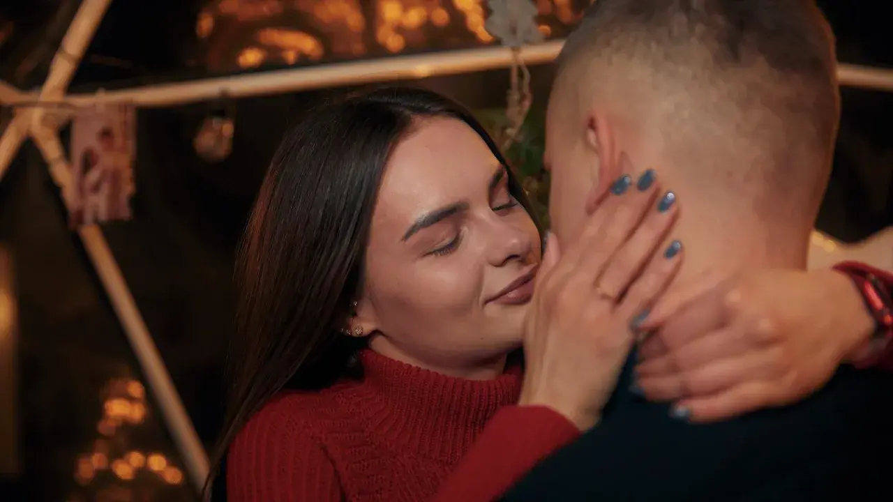 Bliska, intymna chwila pary. Ona zamyka oczy, dotykając jego policzka. Sekret jak rozkochać w sobie faceta na odległość? Bliskość, nawet w oddali.