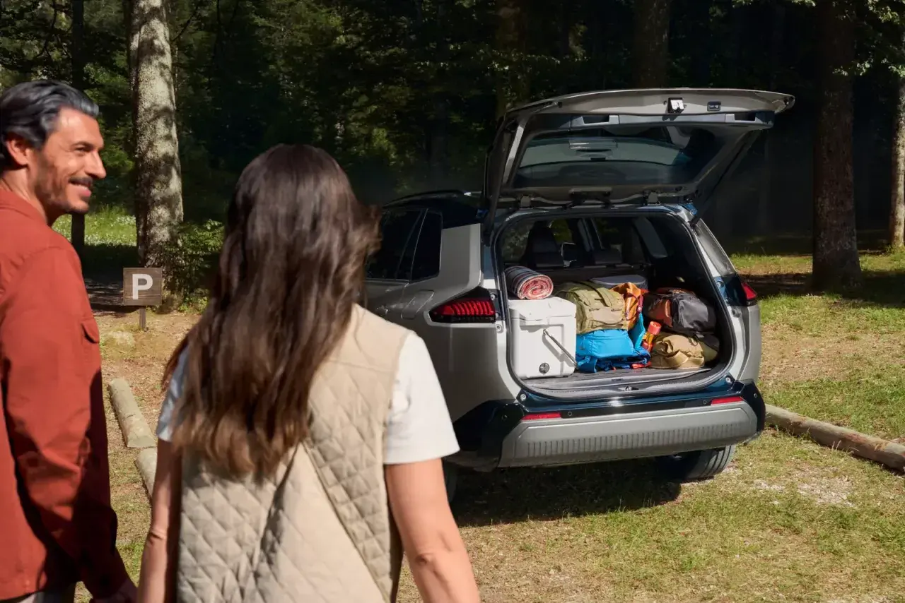 Para wyładowuje bagażnik Toyoty RAV4, gotowa na przygodę. Wymiary bagażnika pozwalają na spakowanie wszystkiego.