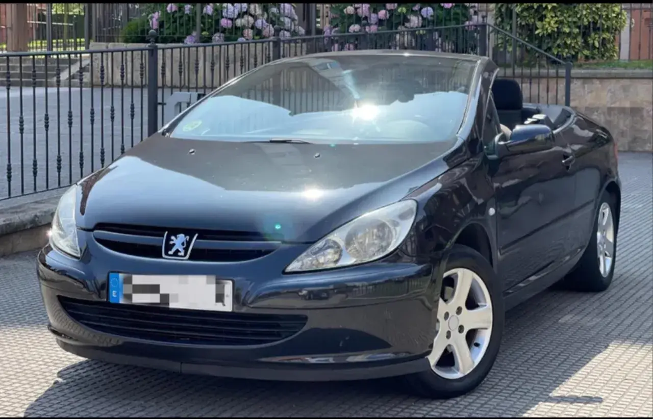 Svart Peugeot 307 CC cabriolet med taket nere. Solen reflekteras i vindrutan, kanske ett tecken på ett kommande peugeot 307 cc problem?