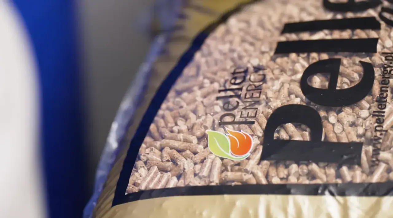 Zbliżenie na worek z pelletem drzewnym. Logo "Pellet Energy" i płomień z liściem. Dowiedz się, jak zrobic pellet.