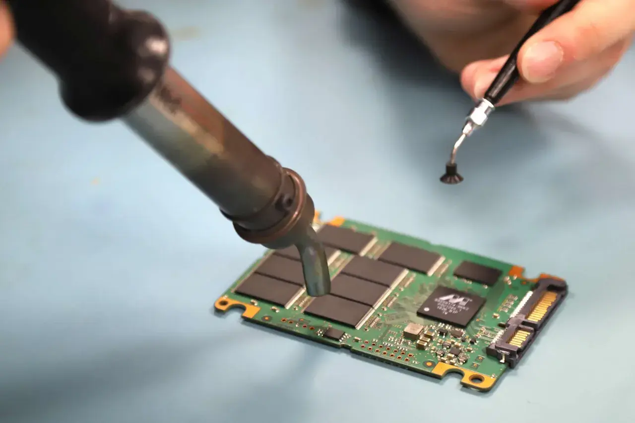 Reparatur einer SSD. Ein Lötkolben erwärmt die Platine, um mögliche ssd defekt symptome zu beheben.