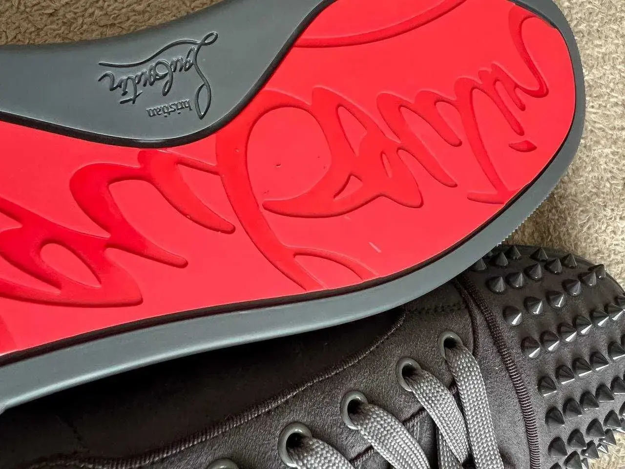 Czerwona podeszwa z logo Christian Louboutin i ćwieki na butach. Zastanawiasz się, ile kosztują buty Christiana Louboutina?