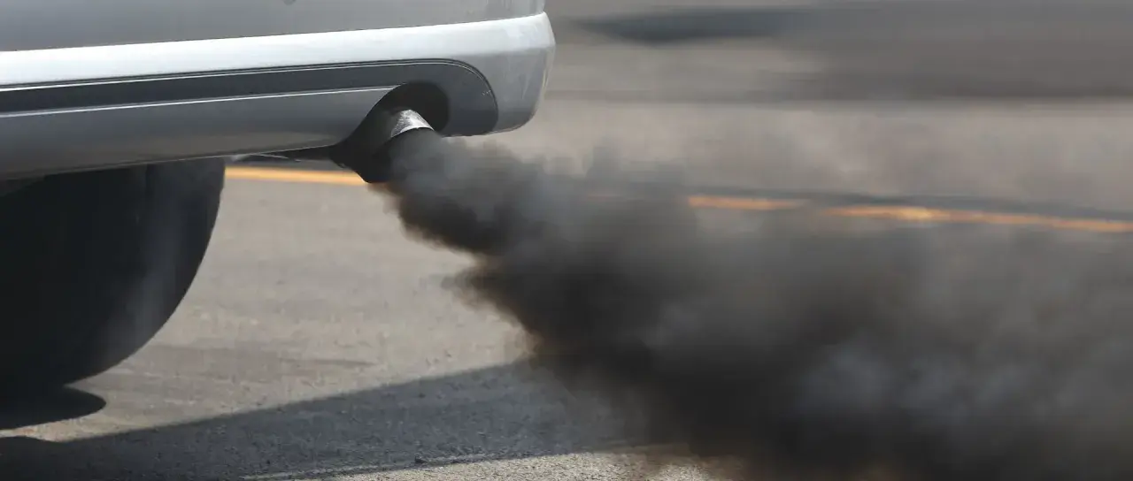 El tubo de escape de un coche emite una densa nube de humo negro, contaminando el aire.