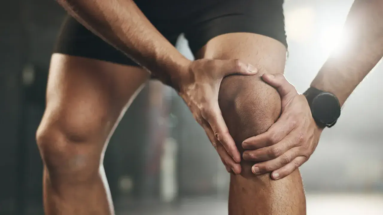 Sportler hält schmerzendes Knie, deutet auf eine mögliche Kreuzbandriss Schwellung hin.