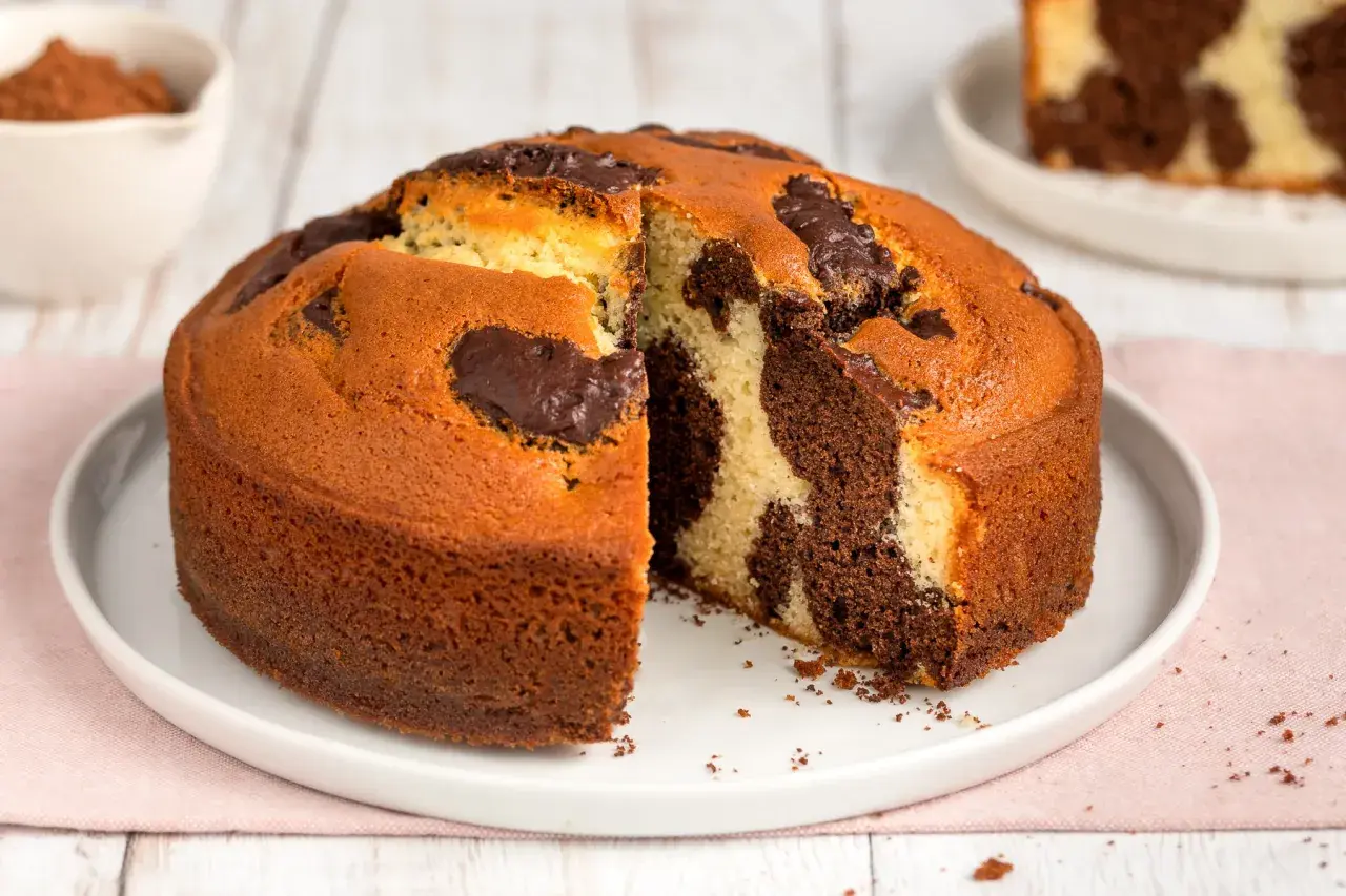 Torta al cioccolato senza burro, con un invitante effetto marmorizzato e una fetta tagliata che ne rivela la morbidezza.
