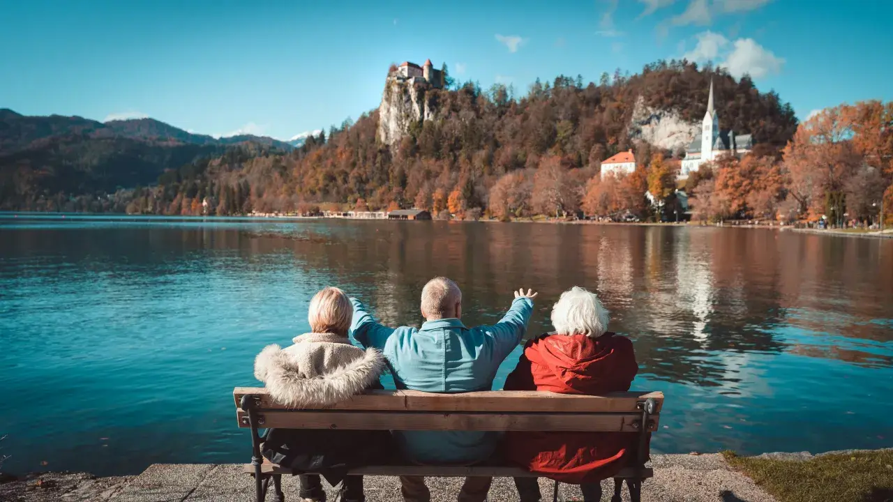 Trzech seniorów cieszy się widokiem zamku na skale i jeziora. Idealne wczasy pod gruszą dla emeryta.