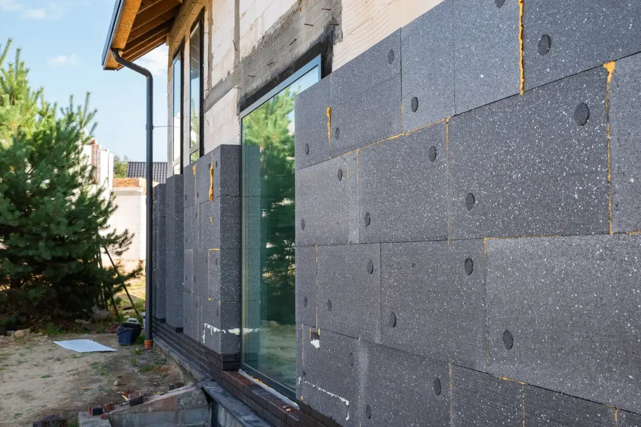 Moderne fassadengestaltung: Dämmplatten aus Polystyrol werden an einer Hauswand angebracht. Ein Fenster ist bereits eingesetzt.