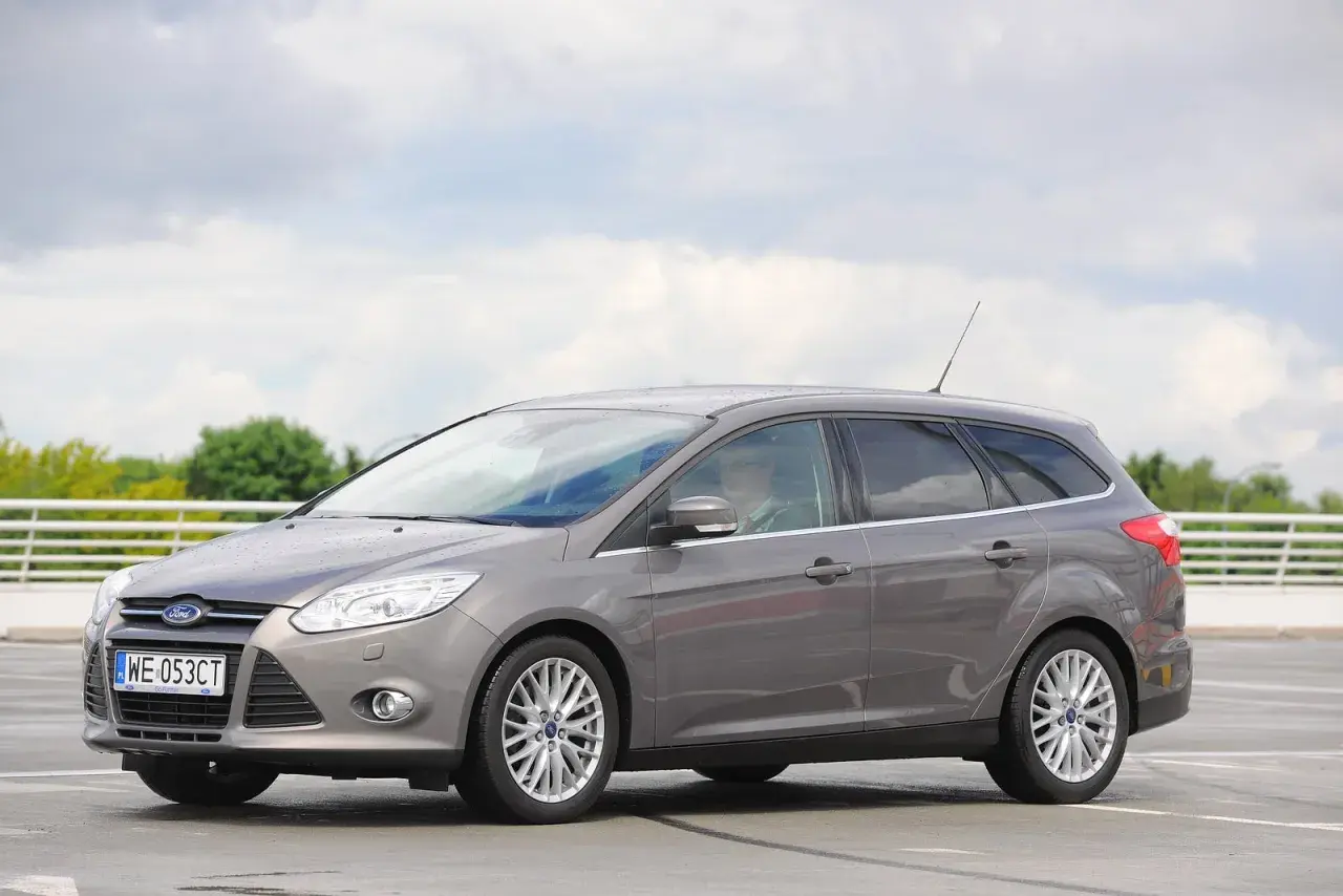 Szary Ford Focus MK3 kombi, z widocznymi reflektorami i felgami. Idealny do miasta i na wakacje, z pewnością z dobrymi żarówkami.