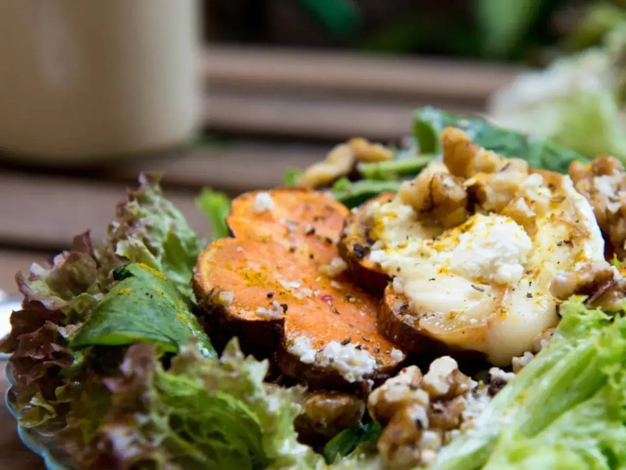 Deliciosa ensalada de batata asada con queso de cabra cremoso, nueces crujientes y hojas verdes frescas.