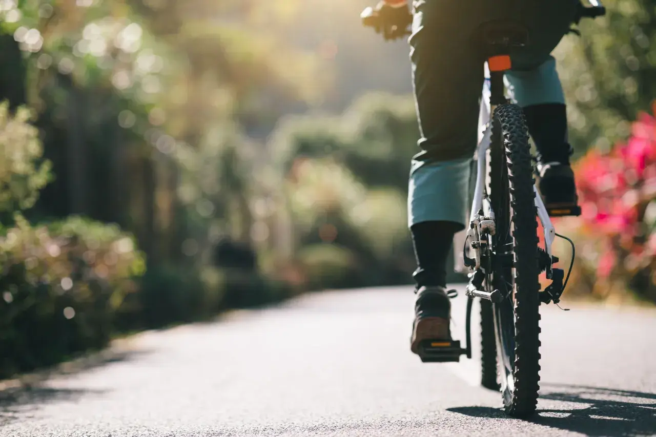 Persona pedaleando en un camino soleado, sintiendo la libertad de soñar con bicicleta.