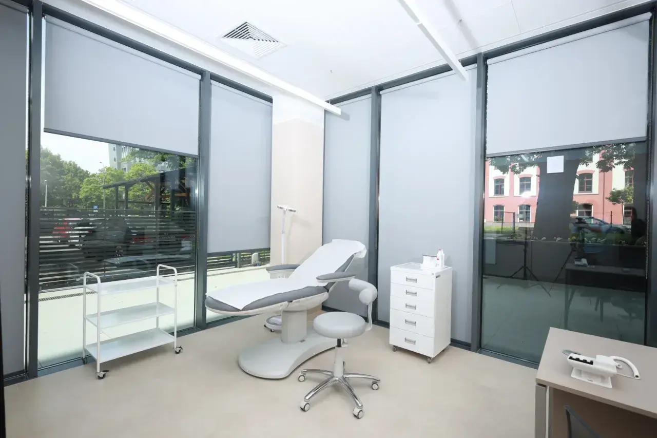 Gabinet dermatologii estetycznej z fotelem zabiegowym, szafką i wózkiem.