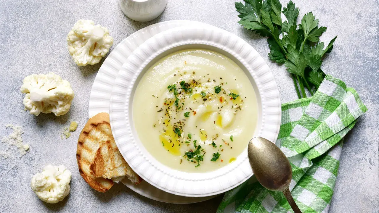 Crema de coliflor, una de las mejores coliflor recetas, servida con pan tostado y perejil fresco.