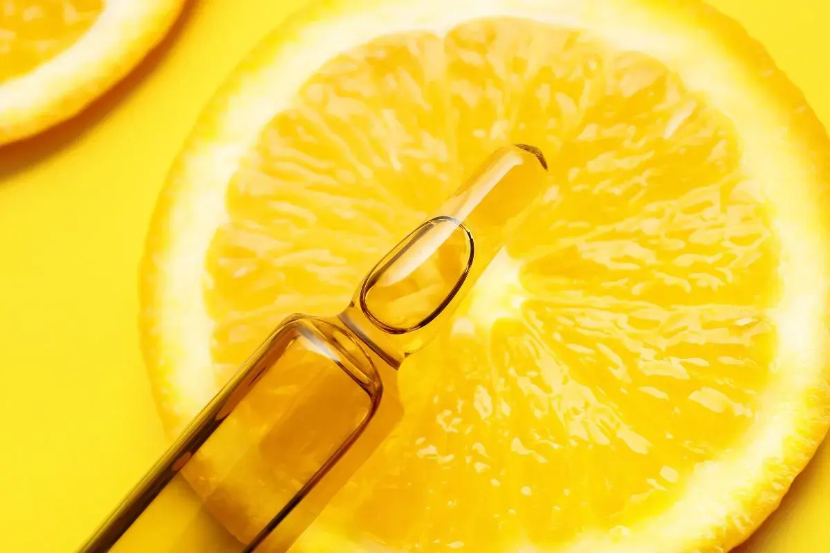 Fetta di limone brillante con fiala di siero alla vitamina C, un concentrato di freschezza e benessere.