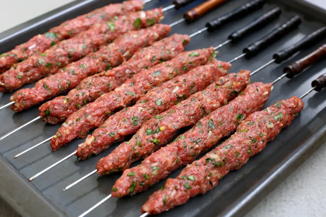 Rå irakisk kebab på spett, redo för grillen. Kryddad färs med lök och örter.