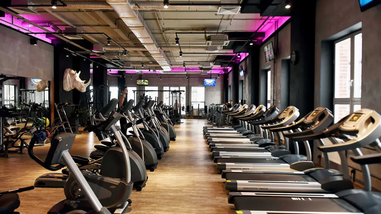 Nowoczesna siłownia z rzędami bieżni i orbitreków. Sprawdź atrakcyjną **Medicover Sport cenę** i zacznij trening!