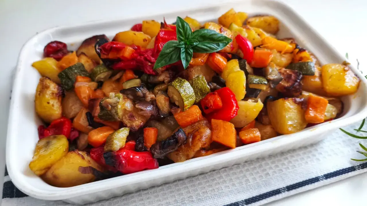 Un plat coloré de recette caponata sicilienne traditionnelle au four, avec des légumes rôtis et une touche de basilic frais.