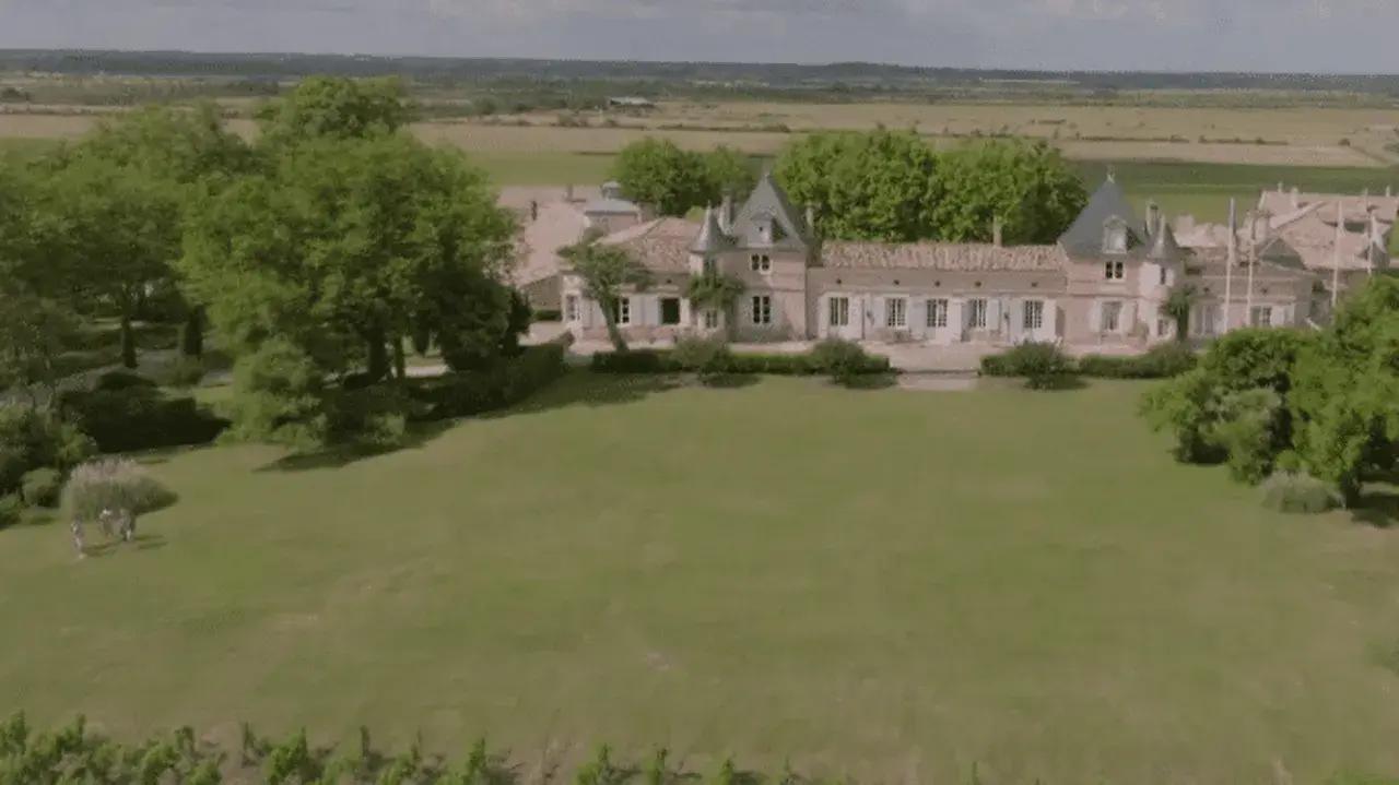 Un magnifique château bordelais, typique de la route des châteaux du Médoc, se dresse au milieu de vignes et d'arbres verdoyants.