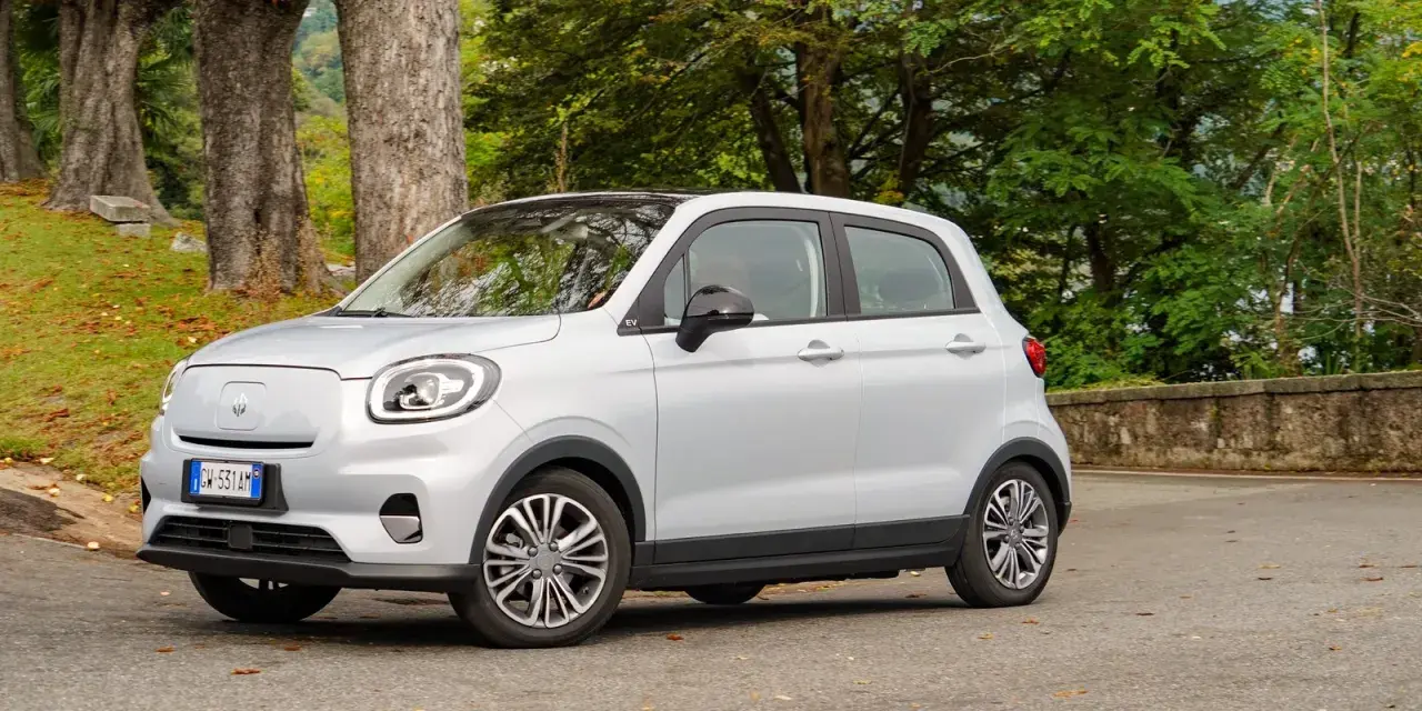 Leapmotor T03 usata, un'auto elettrica compatta e agile, parcheggiata in un contesto naturale con alberi e foglie autunnali.