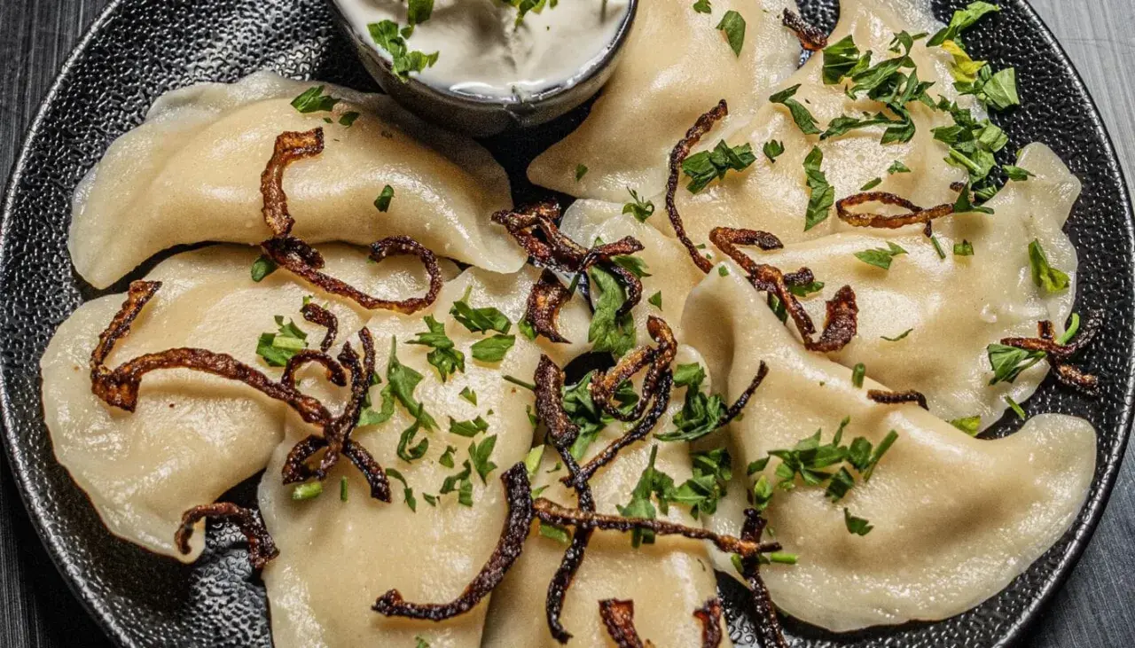 Pyszne pierogi ukraińskie, polane skwarkami i posypane natką pietruszki, podane z kwaśną śmietaną.