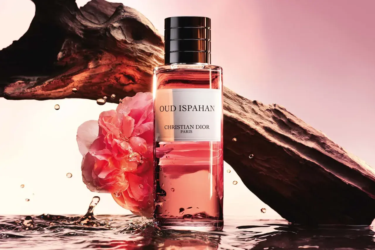 Flakon Dior Oud Ispahan otoczony wodą, różą i fragmentem drewna.