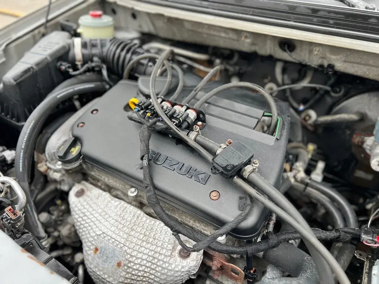 Silnik Suzuki SX4 1.6 benzyna z widocznymi wtryskiwaczami gazu.