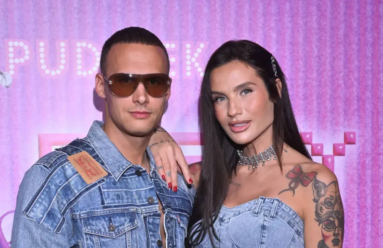 Mateusz Świerczyński z Love Island w dżinsowej kurtce i jego partnerka z naszyjnikiem na tle różowej ściany.
