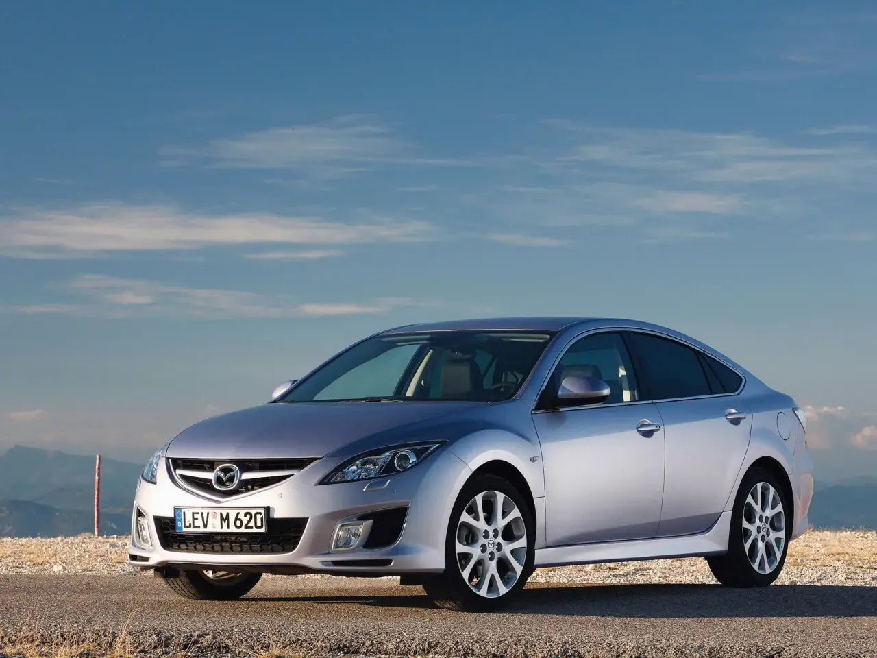 Srebrna Mazda 6 na tle błękitnego nieba. Wiele osób szuka mazda 6 opinie przed zakupem.