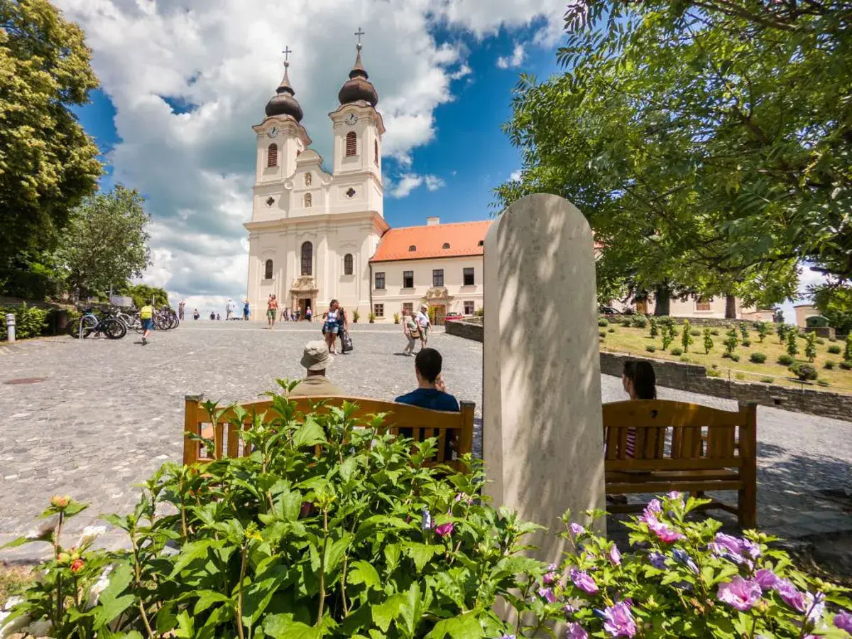 Tihany Balaton: malowniczy plac przed opactwem benedyktynów, z turystami odpoczywającymi na ławkach i podziwiającymi architekturę.