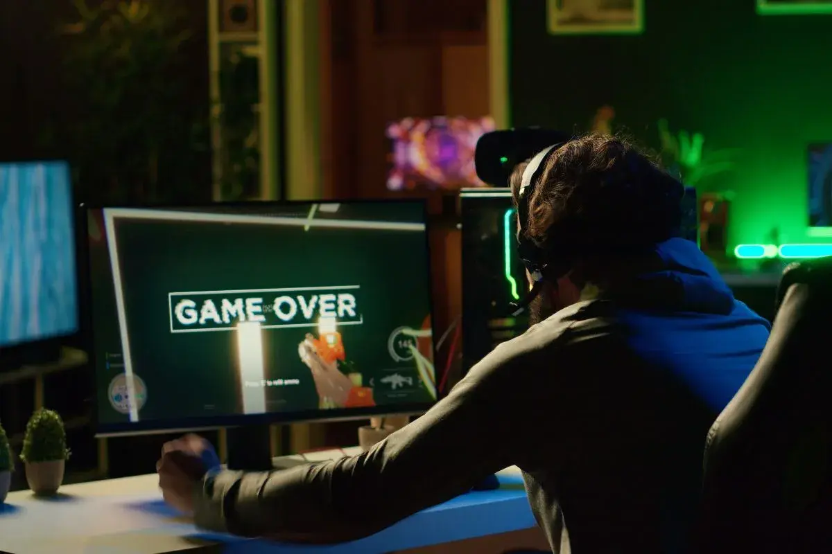 Gracz sfrustrowany przegraną, ekran "GAME OVER". Może to znak, że czas pomyśleć, jak zmniejszyć ping i poprawić swoje wyniki w grach online.